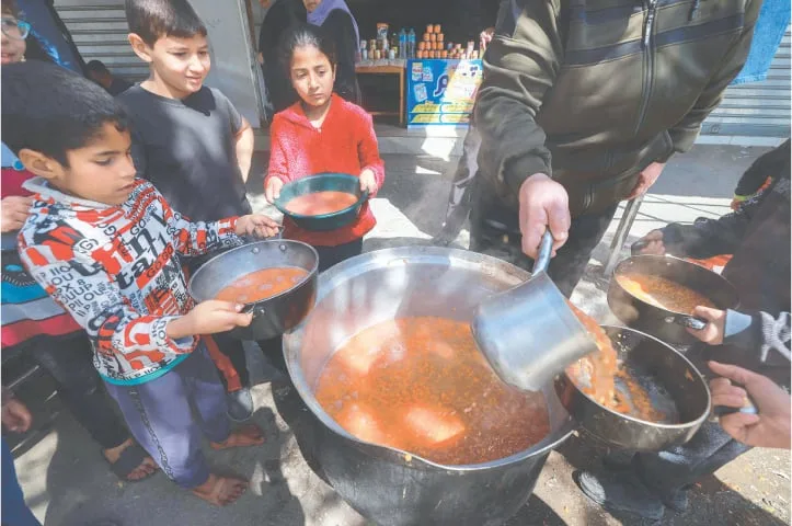 RAFAH: Palestinian children receive cooked food rations as part of a volunteer youth initiative in the southern Gaza Strip, on Tuesday, amid widespread hunger in the occupied territory.