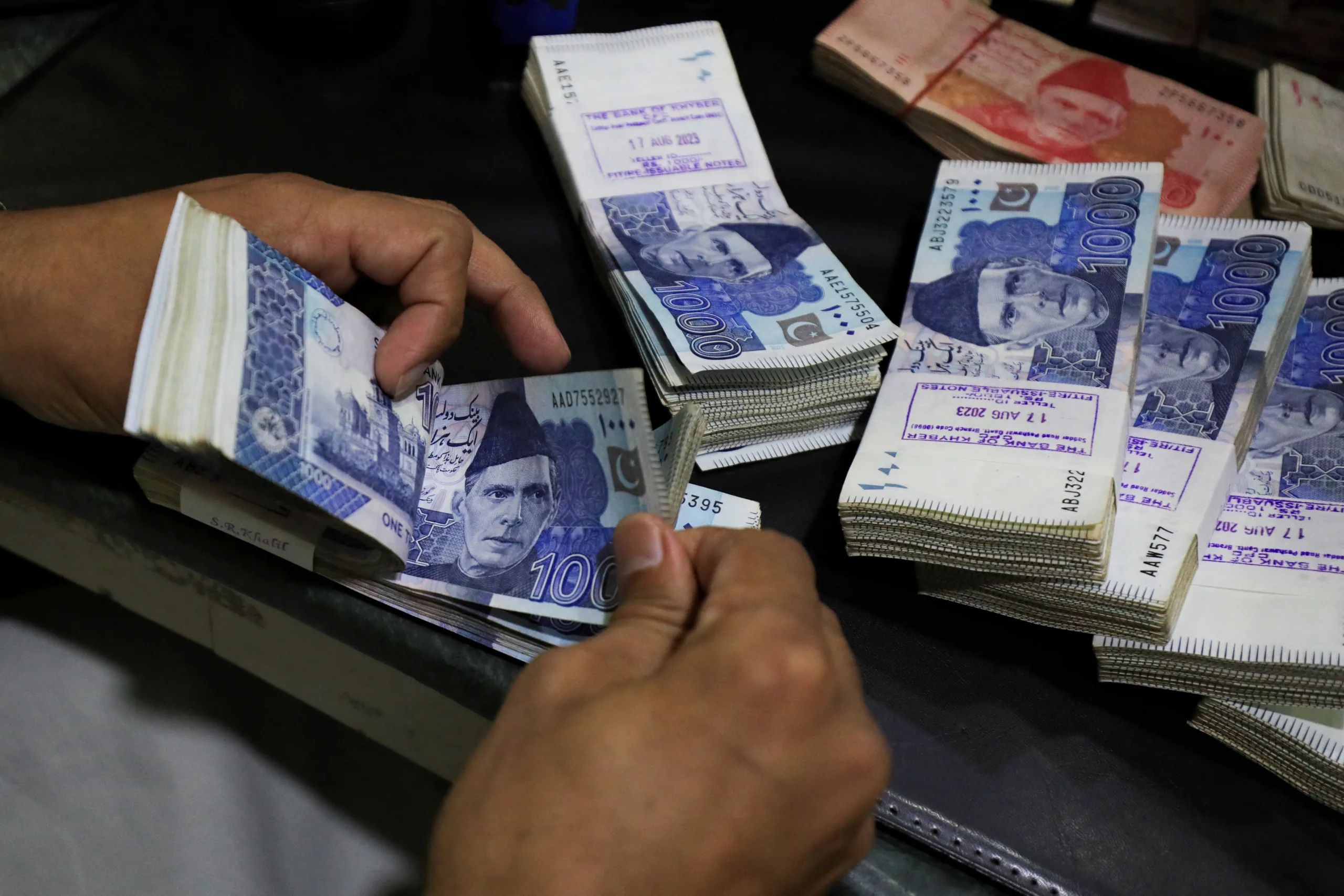 An employee counts Pakistani rupee notes at a bank in Peshawar